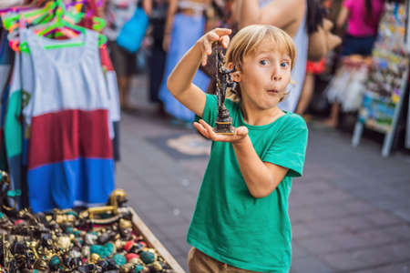 Boy at a market in Ubud, Bali. Typical souvenir shop selling souvenirs and handicrafts of Bali at the famous Ubud Market, Indonesia. Balinese market. Souvenirs of wood and crafts of local residentsの写真素材