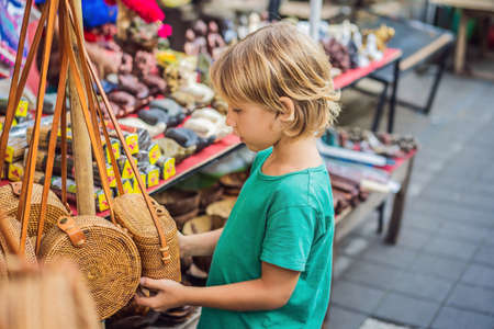 Boy at a market in Ubud, Bali. Typical souvenir shop selling souvenirs and handicrafts of Bali at the famous Ubud Market, Indonesia. Balinese market. Souvenirs of wood and crafts of local residentsの写真素材