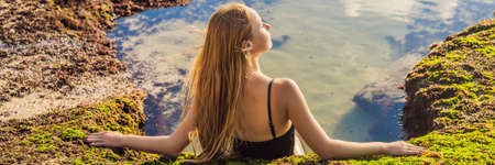 Young woman tourist on Pantai Tegal Wangi Beach sitting in a bath of sea water, Bali Island, Indonesia. Bali Travel Concept BANNER, LONG FORMATの写真素材