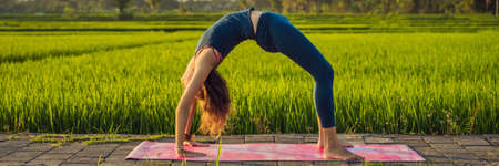 Young woman practice yoga outdoor in rice fields in the morning during wellness retreat in Bali...