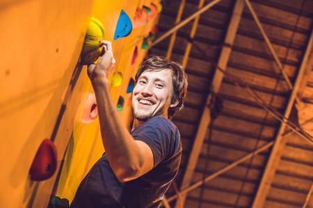 Man climber on artificial climbing wall in bouldering gymの写真素材