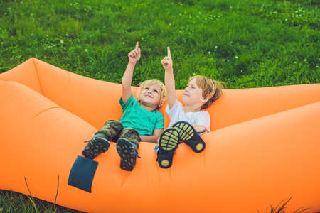 Two cute boys resting on an air sofa in the park.