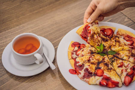 Woman eating delicious strawberry pizza on a balinese tropical nature background. Bali island,...