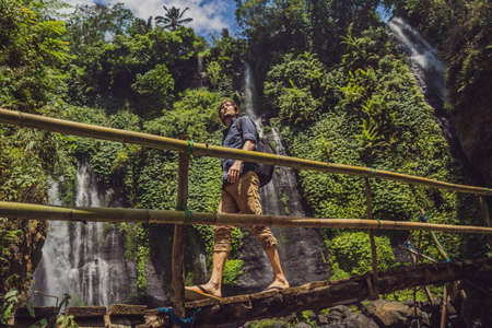 Man in turquoise dress at the Sekumpul waterfalls in jungles on Bali island, Indonesia. Bali Travel...