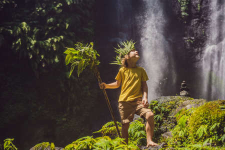 Cute boy depicts the king of the jungle against the backdrop of a waterfall. Childhood without gadgets concept. Traveling with children concept. Childhood outdoors conceptの写真素材