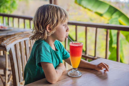 Boy drinks two tone cocktail in a glass in the cafeの写真素材