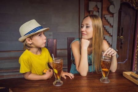 Mom and son tourists in Indonesian food cafe. Traveling with kids concept. What to do with children....