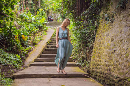 Young woman tourist in Bali walks along the narrow cozy streets of Ubud. Bali is a popular tourist destination. Travel to Bali conceptの写真素材