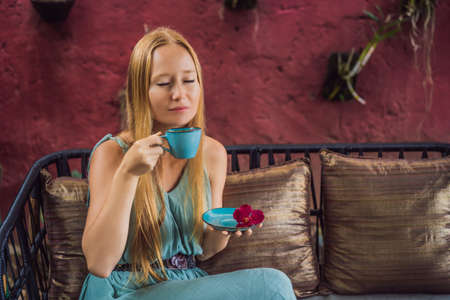 Young woman having a mediterranean breakfast seated at sofa and drinks hot aromatic coffeeの写真素材