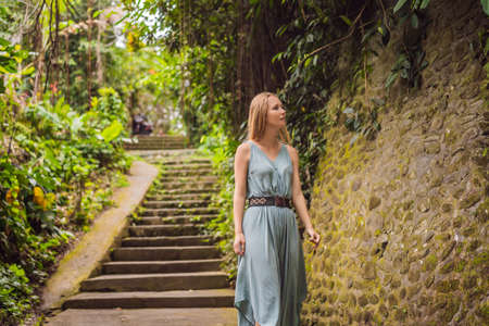 Young woman tourist in Bali walks along the narrow cozy streets of Ubud. Bali is a popular tourist destination. Travel to Bali conceptの写真素材