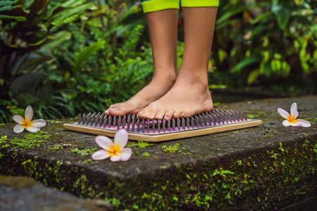 Close-up girl's foot in the leggings for yoga, which stands on the board with nails.の写真素材
