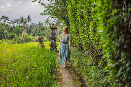 Young woman tourist in Bali walks along the narrow cozy streets of Ubud. Bali is a popular tourist destination. Travel to Bali conceptの写真素材