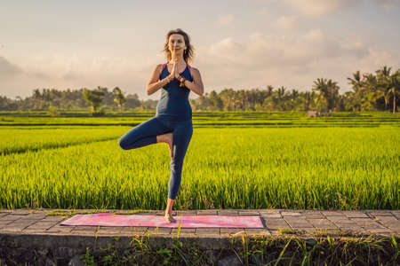 Young woman practice yoga outdoor in rice fields in the morning during wellness retreat in Baliの写真素材