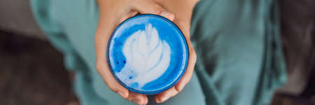 Young woman having a Mediterranean breakfast seated at sofa and drinks Trendy drink: Blue latteの写真素材