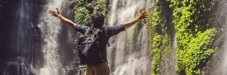 Man in turquoise dress at the Sekumpul waterfalls in jungles on Bali island, Indonesiaの写真素材