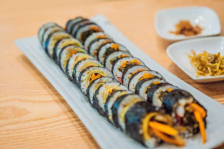 Gimbap or Kimbap is a Korean dish made from steamed white rice bap and various other ingredients, rolled in gim sheets of dried laver seaweed and served in bite-size slicesの写真素材
