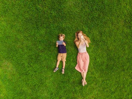 Mom and son are lying on the grass in the park.