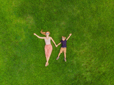 Mom and son are lying on the grass in the parkの写真素材
