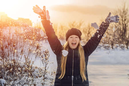 Woman has fun in winter, throws snowの写真素材