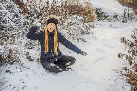 Girl throwing snowball at camera smiling happy having fun outdoors on snowing winter day playing in snow.の写真素材