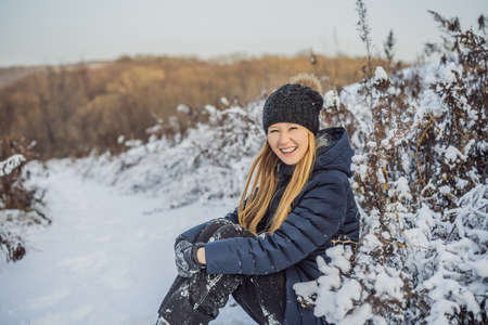 Enjoying the first snow: young woman outdoors on a lovely forest path watching the snowflakes fallingの写真素材