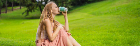 Dreamy young woman having a cup of coffee outsideの写真素材