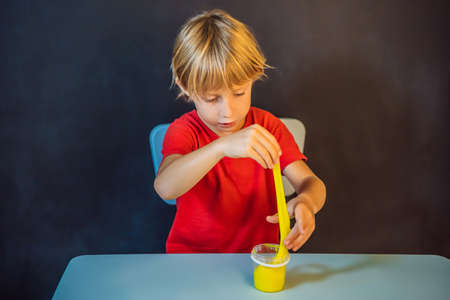 Boy playing hand made toy called slime. Child play with slime. Kid squeeze and stretching slimeの写真素材