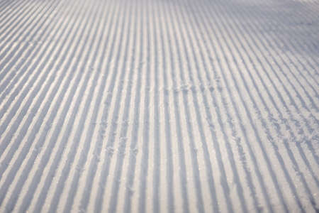 perfectly groomed empty ski run on a sunny winter day.