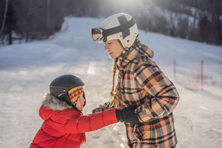 Mother teaches son snowboarding. Activities for children in winter. Childrens winter sport. Lifestyleの写真素材
