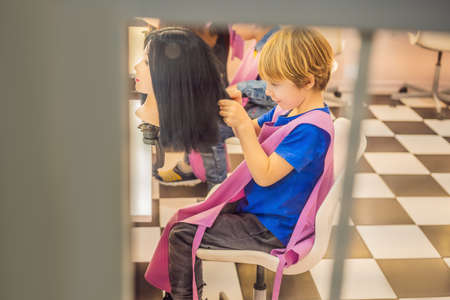 boy hairdresser, day of choice of profession, play at the hairdresser in the children's beauty salon, hairstylist, hairdressing, barber job.の写真素材