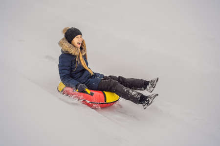 Woman sliding down on snow tubes