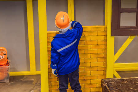 A boy plays in the builder in construction clothes and a helmet.の写真素材