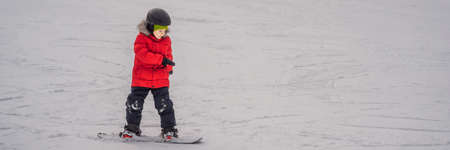 Little cute boy snowboarding. Activities for children in winter. Children's winter sport. Lifestyle. BANNER, LONG FORMATの写真素材
