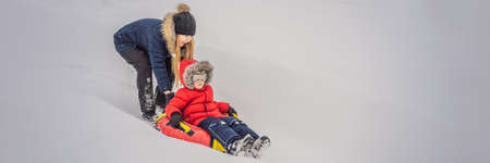 mom son ride on an inflatable winter sled tubing. Winter fun for the whole family. BANNER, LONG FORMATの写真素材