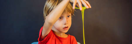 Boy playing hand made toy called slime. Child play with slime. Kid squeeze and stretching slime BANNER, LONG FORMATの写真素材