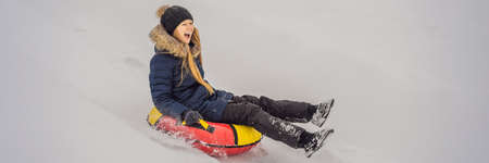 winter, leisure, sport, friendship and people concept - woman sliding down on snow tubes BANNER, LONG FORMATの写真素材