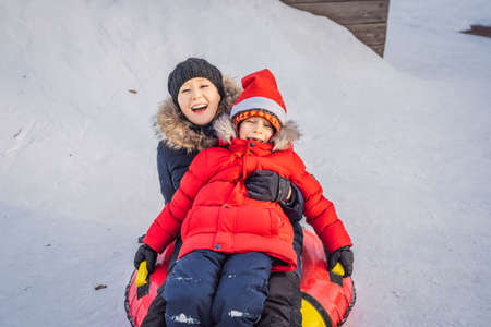 mom son ride on an inflatable winter sled tubing. Winter fun for the whole family