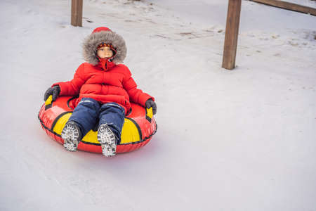 Child having fun on snow tube. Boy is riding a tubing. Winter fun for childrenの写真素材