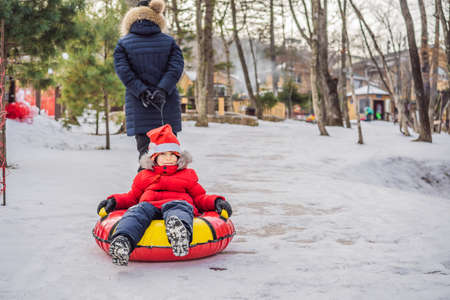 mom son ride on an inflatable winter sled tubing. Winter fun for the whole familyの写真素材