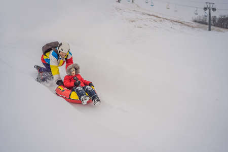 Dad and son have fun on tubing in the winter. Winter fun for the whole family.