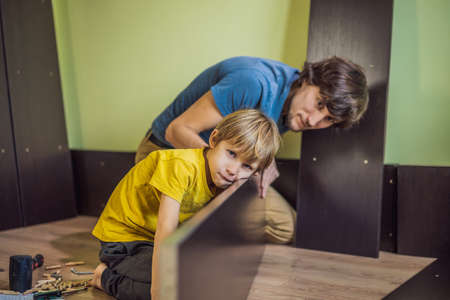 Father and son assembling furniture. Boy helping his dad at home. Happy Family conceptの写真素材