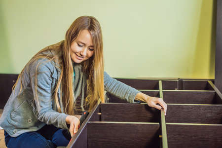 Caucasian woman using screwdriver for assembling furnitureの写真素材