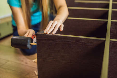 Caucasian woman using screwdriver for assembling furniture.
