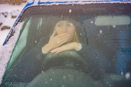 Woman in a car during a snowfall, problems on the road.の写真素材