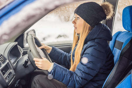 Woman in a car during a snowfall, problems on the road
