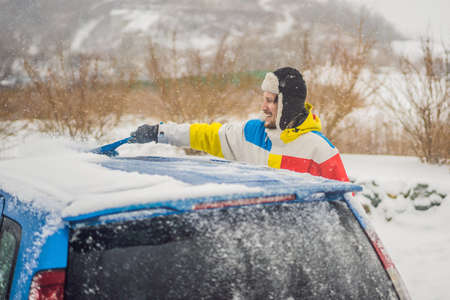 Removing snow from car with a brush.