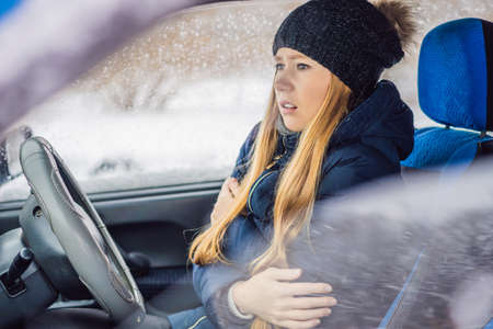 Woman in a car during a snowfall, problems on the road