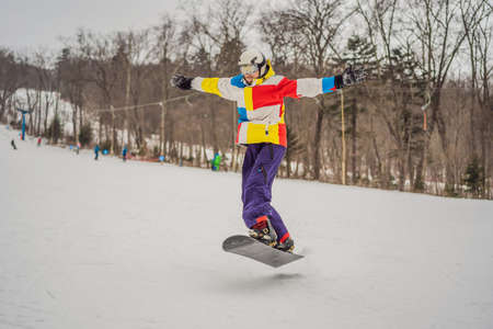 Young man jumping with a snowboard in the mountainsの写真素材
