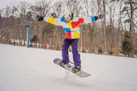 Young man jumping with a snowboard in the mountainsの写真素材