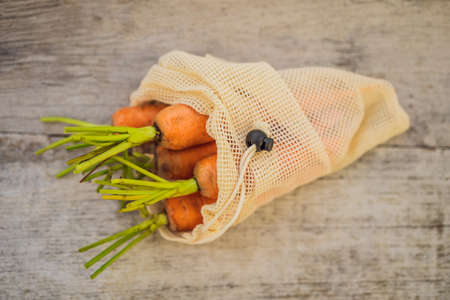Carrot in a reusable bag on a stylish wooden kitchen surface. Zero waste concept.の写真素材